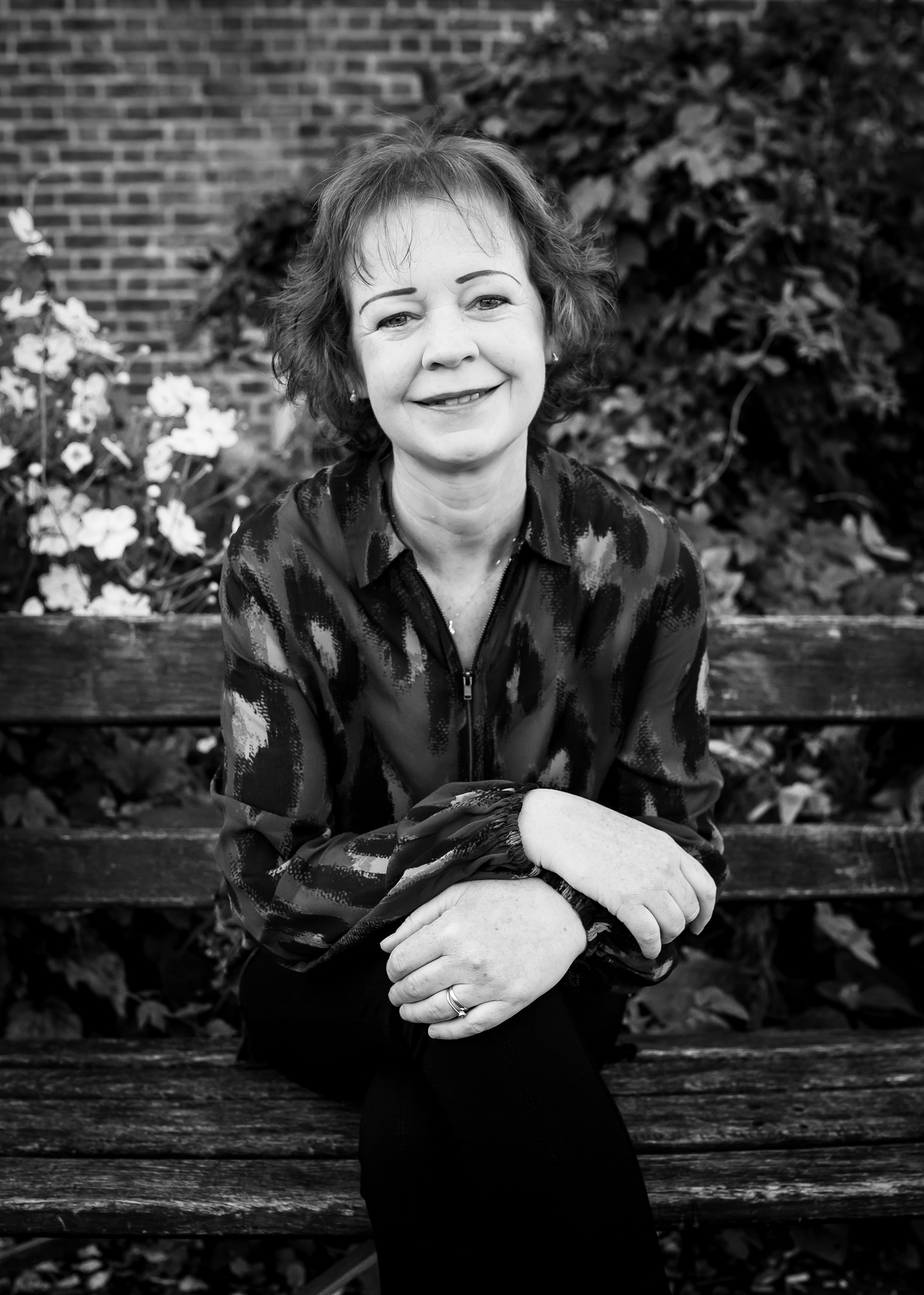 Black & white photo of Joan Faria sitting on a park bench