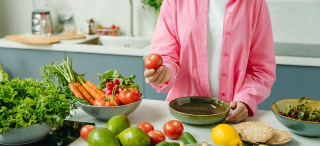 Woman at kitchen worktop preparing vegetables and fruit