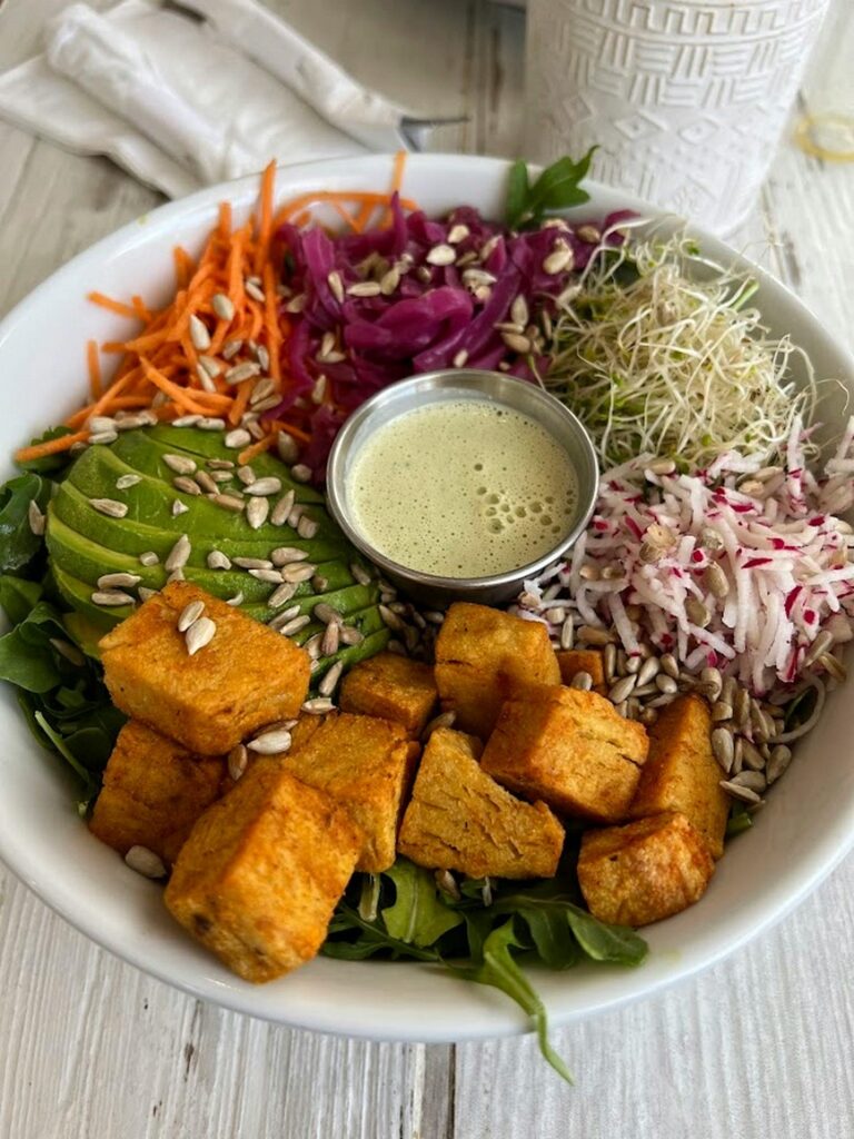 Buddha bowl with tofu, avocado, carrot, red cabbage, seeds, sprouts and a creamy dressing
